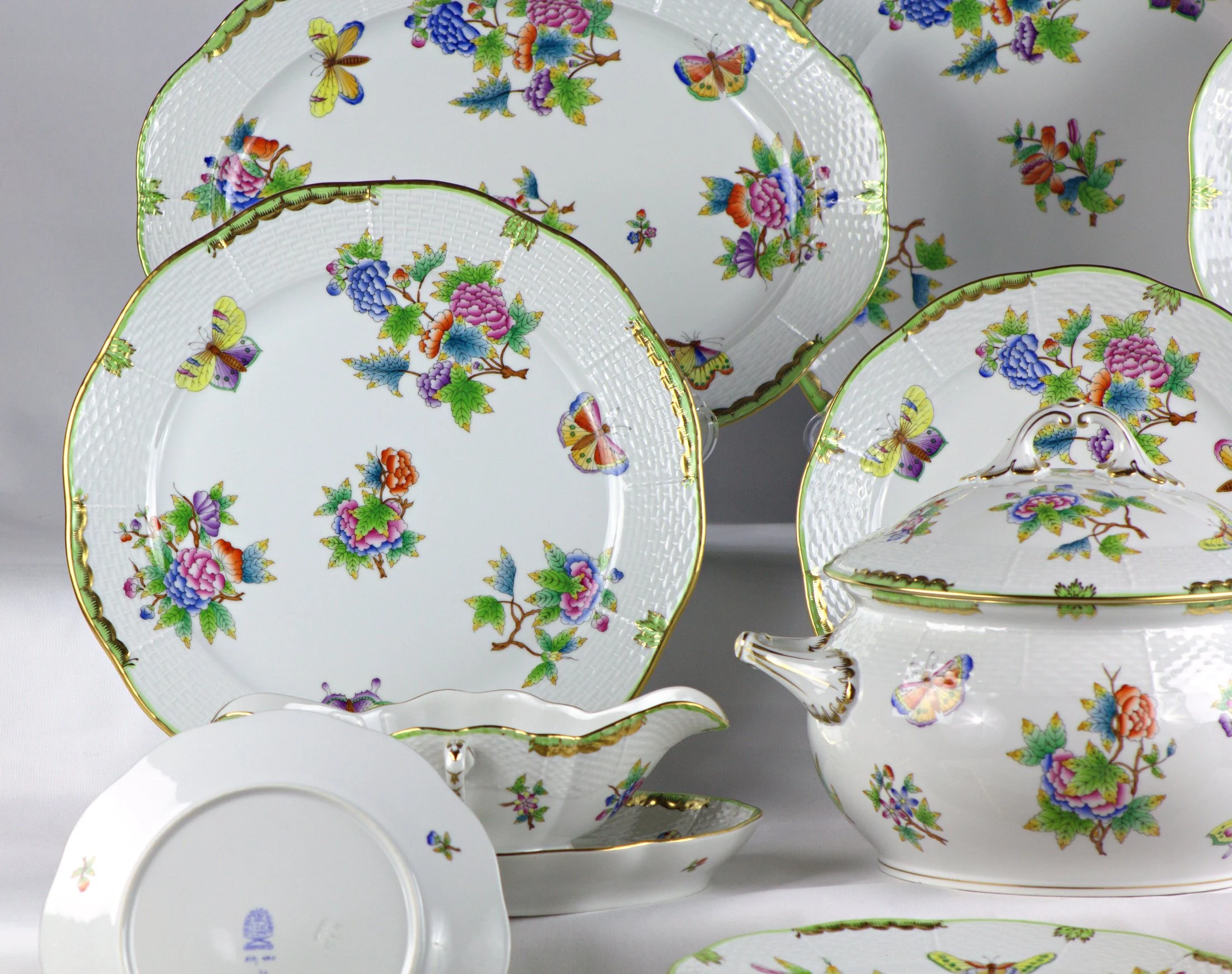 Piatti e salsiera, vista del lato sinistro del servizio Herend Queen Victoria, con decoro di fiori e farfalle.