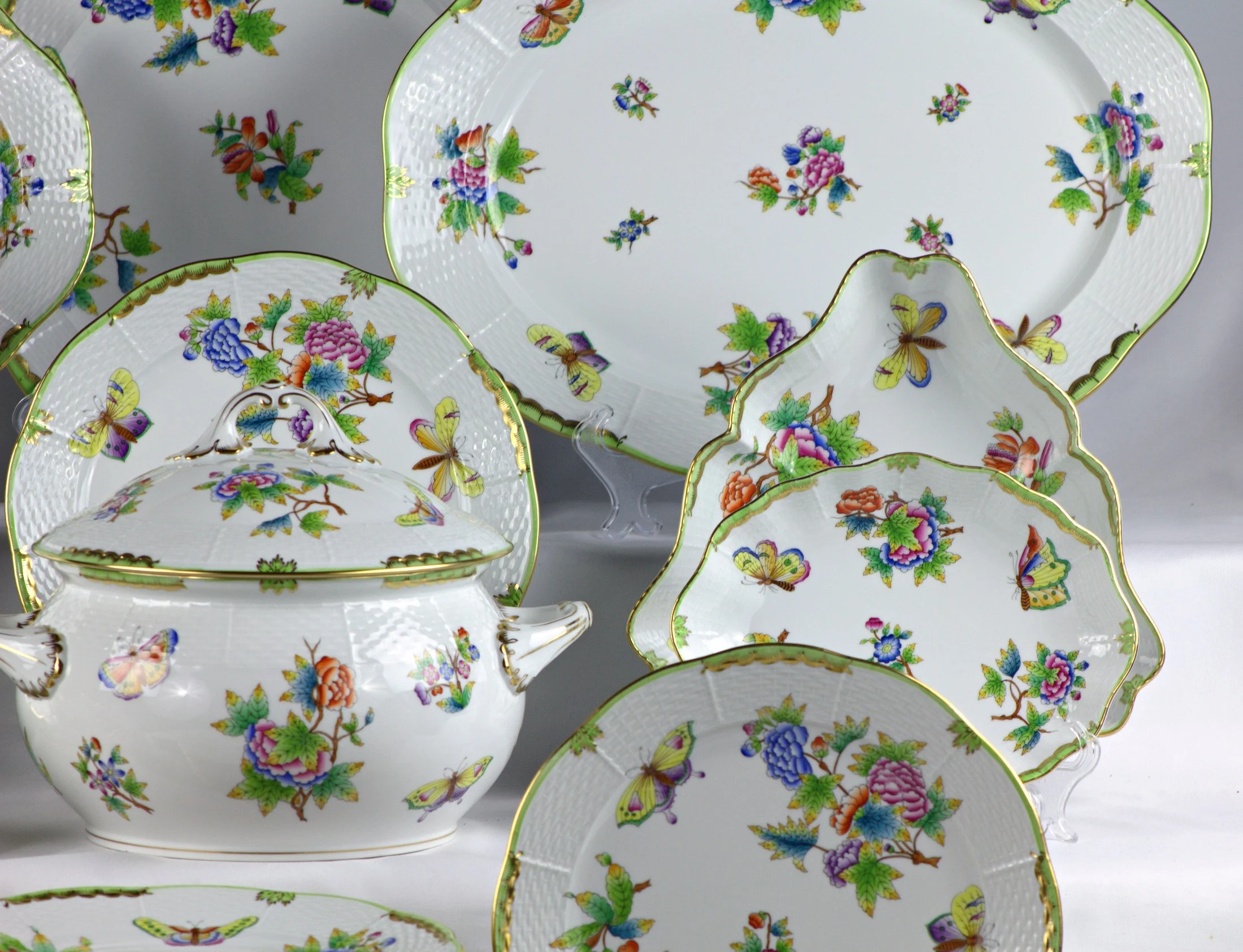 Zuppiera e piatti sagomati, vista del lato destro del servizio Herend Queen Victoria, con decoro di fiori e farfalle.