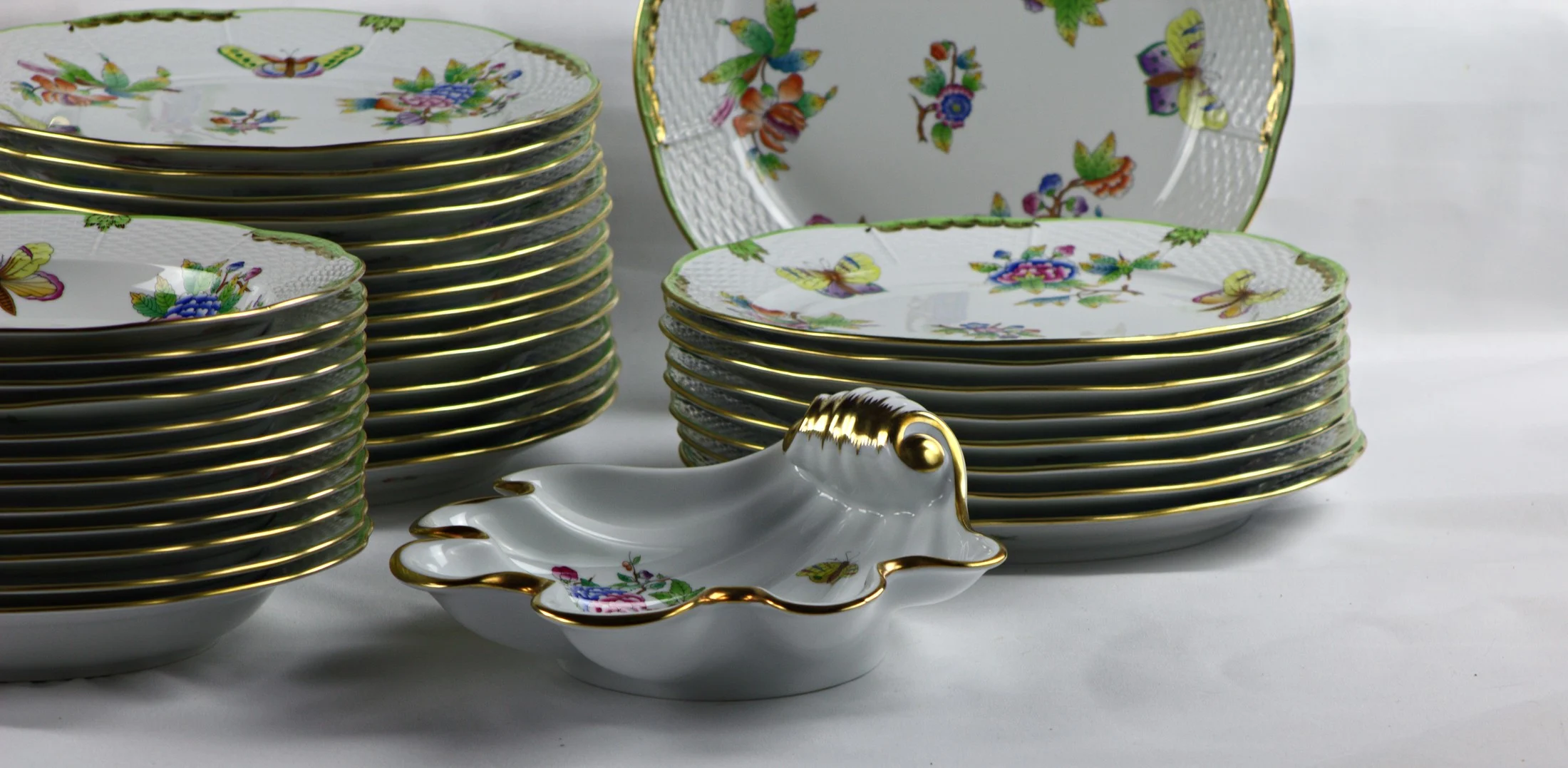 Piccolo recipiente sagomato e piatti impilati del servizio Herend Queen Victoria, con decoro di fiori e farfalle.