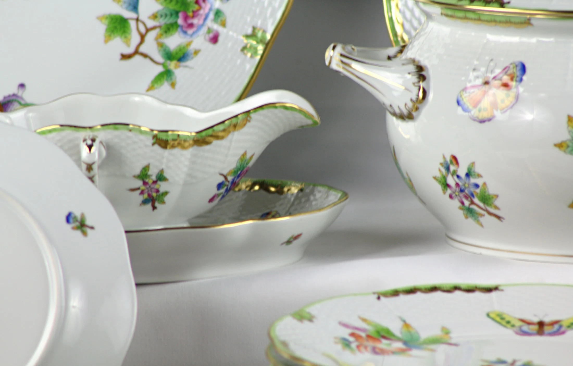 Salsiera con piatto sottostante del servizio Herend Queen Victoria, con decoro di fiori e farfalle.
