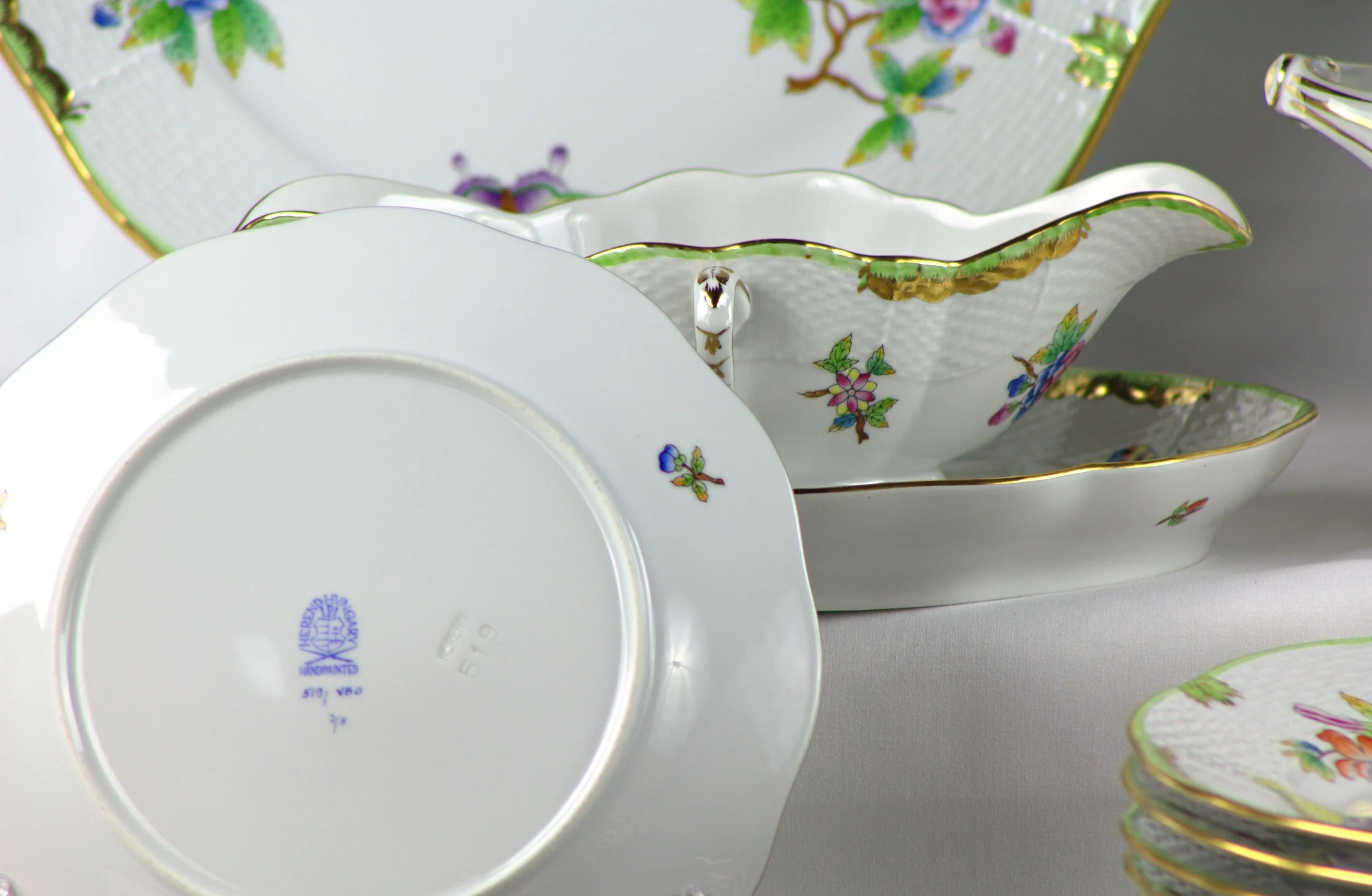 Marchio Herend sul fondo di un piatto del servizio Herend Queen Victoria, con decoro di fiori e farfalle.