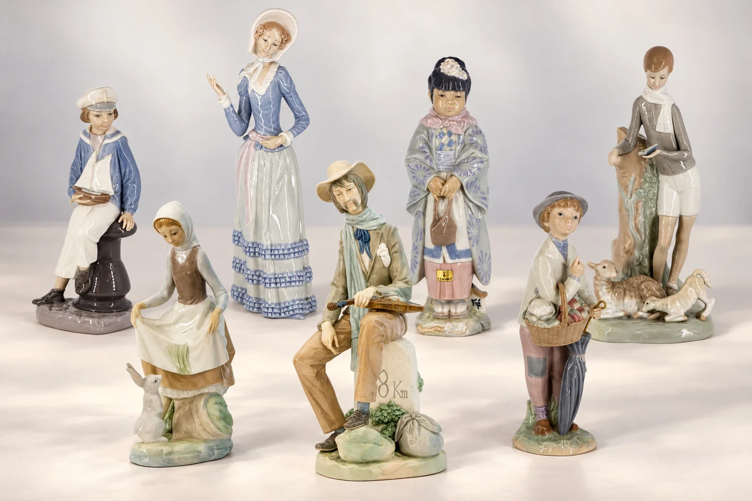 Composizione con sette statuine Lladró: dama, ragazza in costume, ragazza con coniglio, suonatore, marinaio e due ragazzi